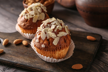 Tasty almond muffins on wooden board, closeup