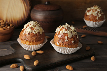 Board with tasty almond muffins on wooden table