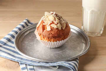 Plate with tasty almond muffins and milk on wooden table