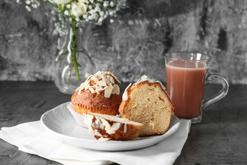 Plate with tasty almond muffins and cup of coffee on grey table