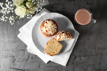Plate with tasty almond muffins and cup of coffee on grey table