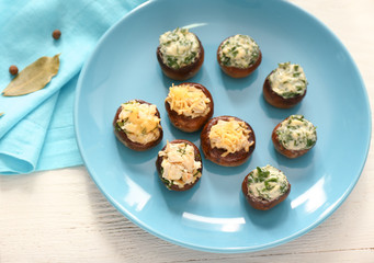 Plate with tasty stuffed mushrooms on white table