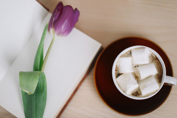 Beautiful tulip with book and cup of coffee on wooden background. Spring concept. top view. flatlay 