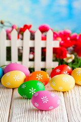Colorful Easter eggs and white fence on nature background