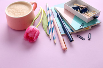 Stylish stationery with cup of coffee on color background