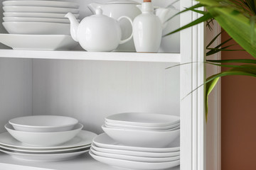 Set of clean dishes on shelves in kitchen