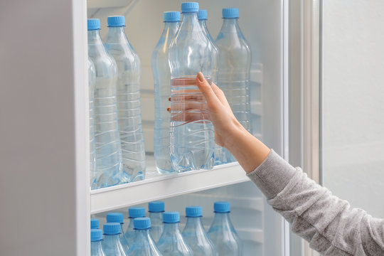 Woman Taking Bottle Of Water From Fridge In Shop