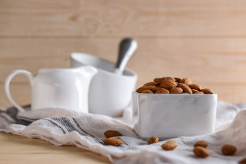 Bowl with tasty almonds on wooden table