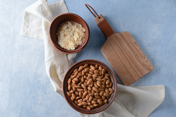 Bowls with tasty almonds and flakes on color table