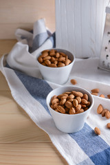 Bowls with tasty almonds on wooden table