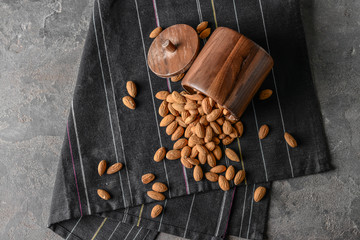 Wooden jar with tasty almonds on grey table
