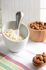 Mortar with tasty almond flour and nuts on table