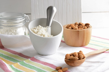 Mortar with tasty almond flour and nuts on table