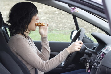 JEUNE FEMME QUI MANGE EN CONDUISANT