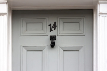Obraz na płótnie Canvas House number fourteen on a beige door with a door knocker in the form of a black hand 