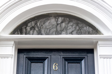 House number six on an outside blue door with half round window at the top