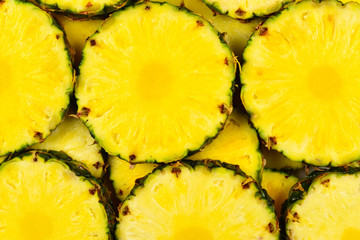 Pineapple juicy yellow slices background. Top view.