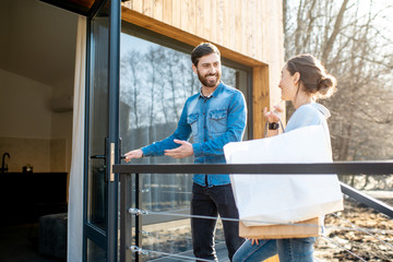 Young couple entering home carrying shopping bags. Happy purchase and modern living concept