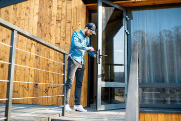 Fototapeta premium Workman repairing entrance door lock of the modern house or hotel during the sunny weather outdoors