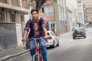 Young Asian man riding his bike through city streets