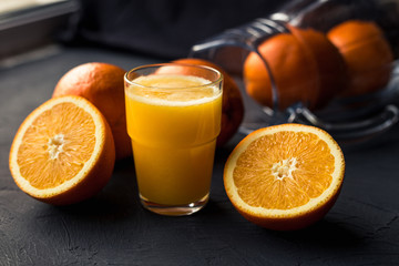Fresh orange juice and fresh fruit oranges on a black background