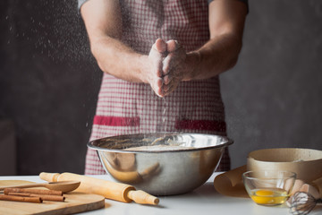 A handful of flour with egg on a rustic kitchen. Against the background of men's hands knead the dough