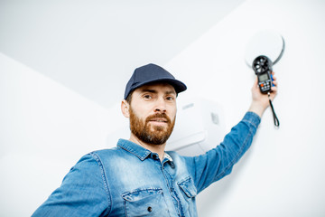 Handyman checking the speed of air ventilation with measuring tool on the white wall background