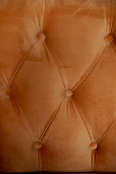 Upholstery orange sofa or chair . Velvet with buttons. Texture