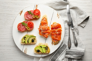 Wooden board with fresh tasty bruschettas on table
