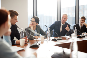 Portrait of cheerful businesswoman looking at colleague during business meeting in conference room, copy space