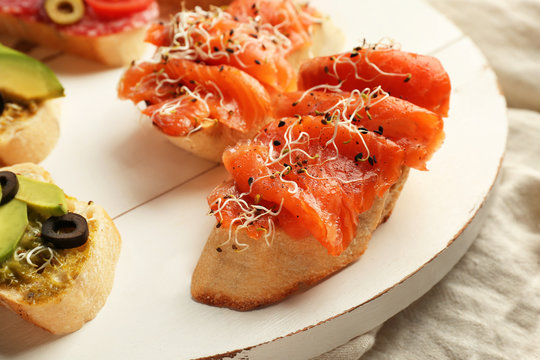 Fresh tasty bruschettas on wooden board, closeup
