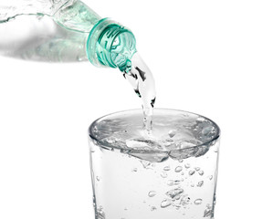 Water pouring from bottle into glass on white background