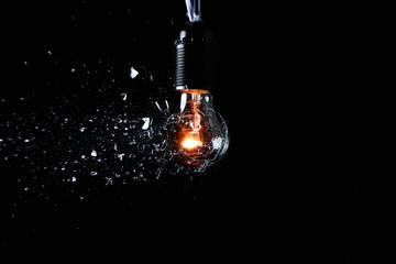 Breaking of light bulb on dark background