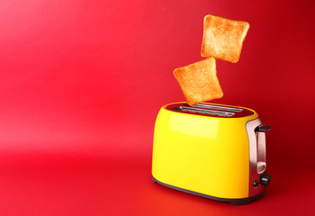 Toaster with bread slices on color background