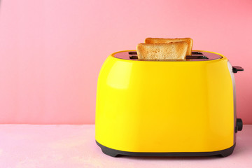 Toaster with bread slices on color background