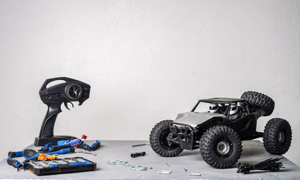 Radio-controlled car models: a table with scattered tools for repairing rc buggy models and a control panel.