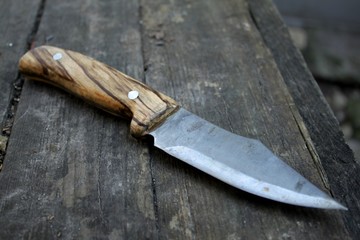 Beautiful homemade dangerous knife with a wooden handle lies on the table