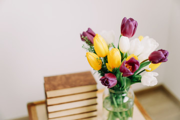 Bouquet of beautiful tulips. Mix of spring tulips flowers. Fresh spring flowers and books on white background. 