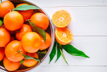 Tangerines (oranges, clementines, citrus fruits) with green leaves over wooden background with copy...