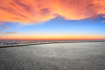 Empty asphalt ground and city skyline with beautiful clouds at sunset