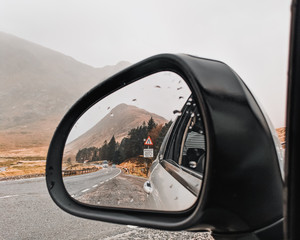 Fototapeta premium Reflection of a road and mountain in a car mirror