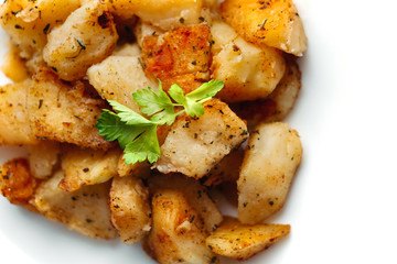 Delicious gold fried potato with herbs on big rounded white plate. Tasty rustic dish for dinner on white background.