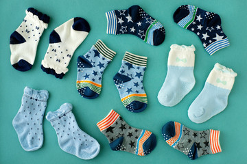 Baby socks on a turquoise background. View from above. Lots of socks for kids scattered on the...