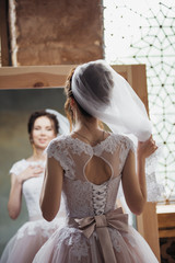 Fototapeta premium The bride gathers in the morning near the mirror and adjusts her hair.