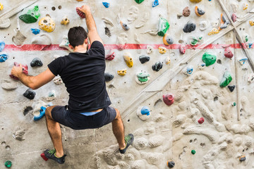 Man practicing rock climbing on artificial wall indoors. Active lifestyle and bouldering concept..