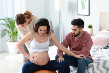 Pregnant couple with doula at home - obrazy, fototapety, plakaty