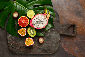 Assortment of exotic fruits with tropical leaf on wooden board