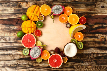 Board with assortment of tropical fruits on wooden background