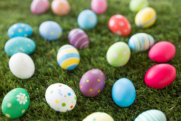 Fototapeta na wymiar easter, holidays and tradition concept - colored eggs on artificial grass