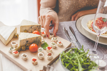 Woman's hand taking cheese from wooden board